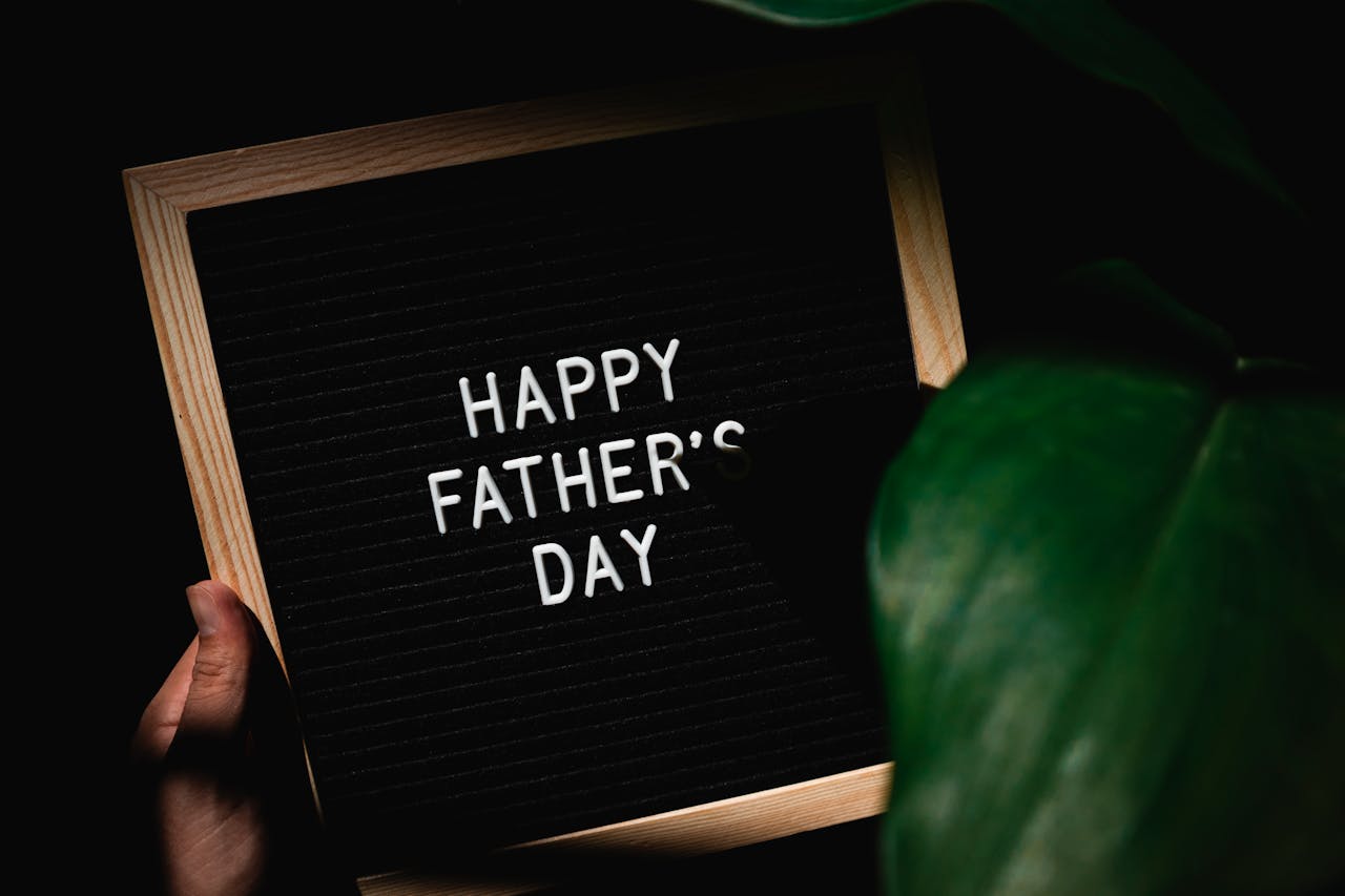 Offerings Letter board with 'Happy Father's Day' message held by hand, surrounded by leaves.